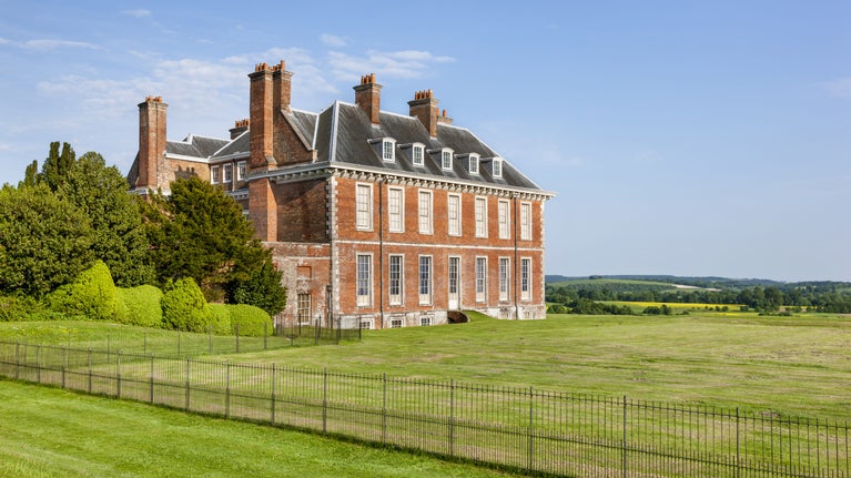 A view of the red brick house and parkland at Uppark